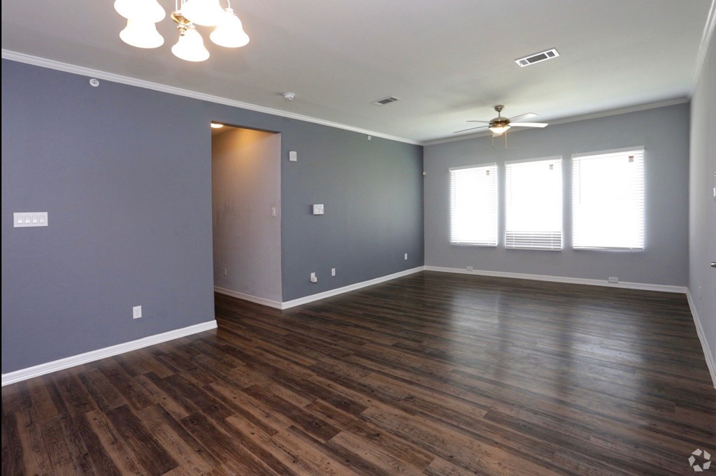 an empty living room with wood floors and a ceiling fan