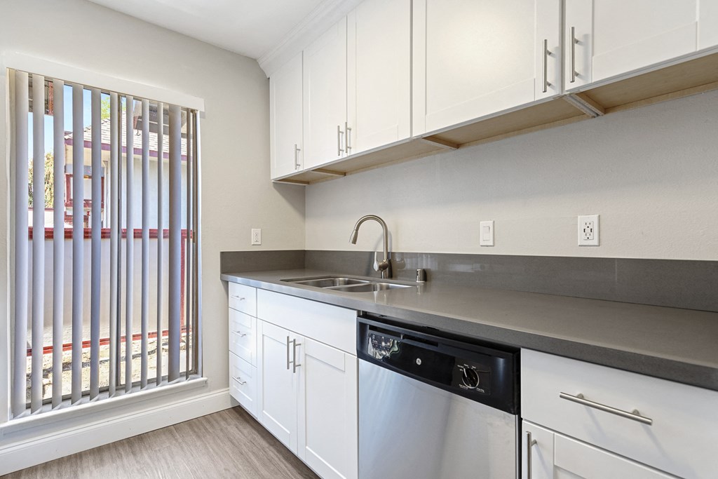 an empty kitchen with white cabinets and a window