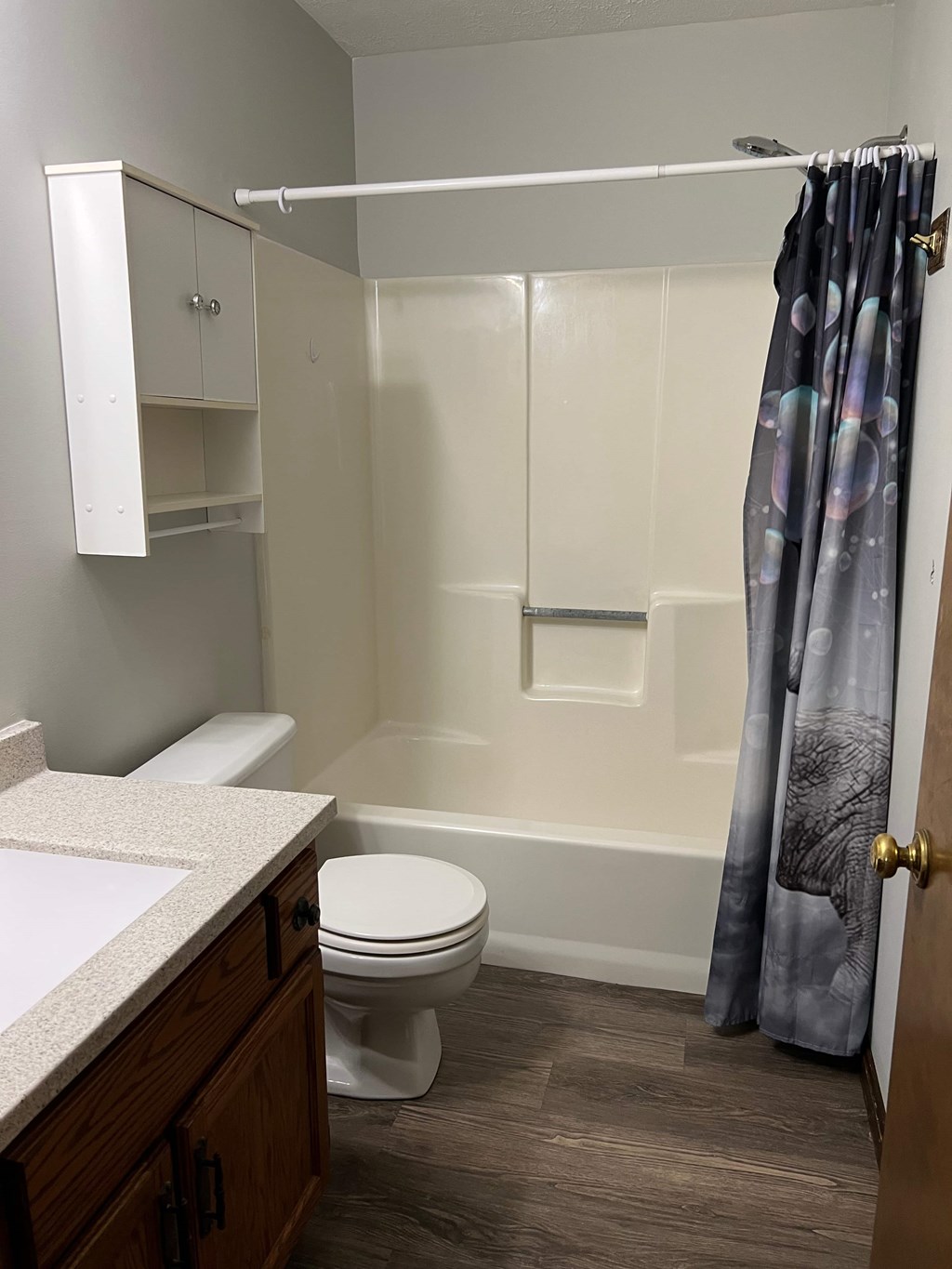 A white toilet sits in a bathroom with a white tub and a shower curtain.