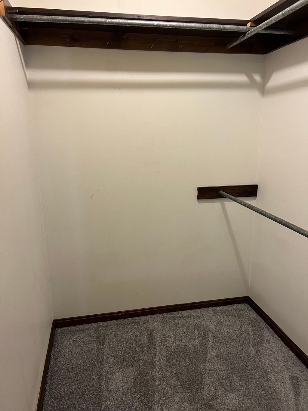 A small, empty room with a carpeted floor and a wooden beam on the ceiling.