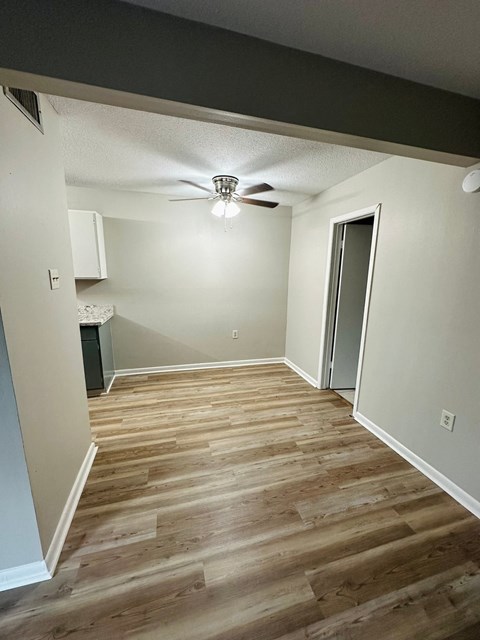 a renovated living room with wood floors and a ceiling fan