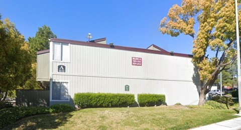 A white building with a red roof and a sign on it.