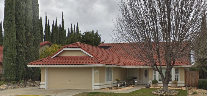 a house with a red tile roof and a tree