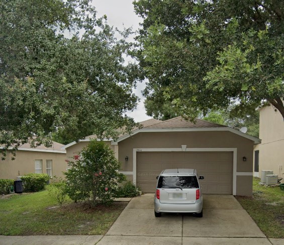 A silver minivan is parked in front of a tan garage.