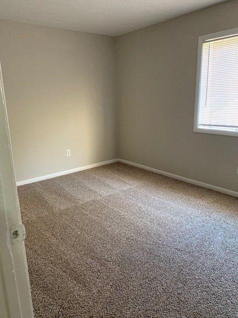 an empty room with a carpeted floor and a window