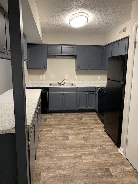 a kitchen with dark blue cabinets and a wood floor