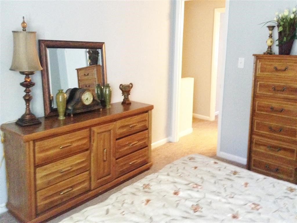 a bedroom with a bed and a dresser with a mirror
