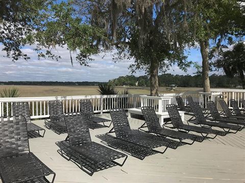 a row of chairs on a deck overlooking a lake