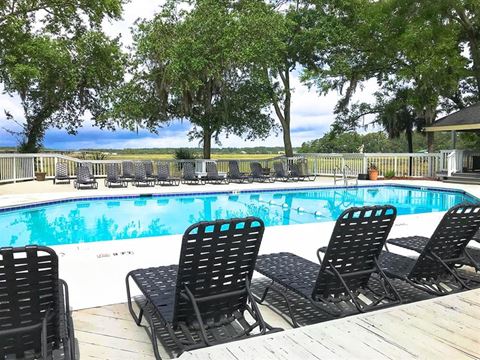 a swimming pool with black chairs around it