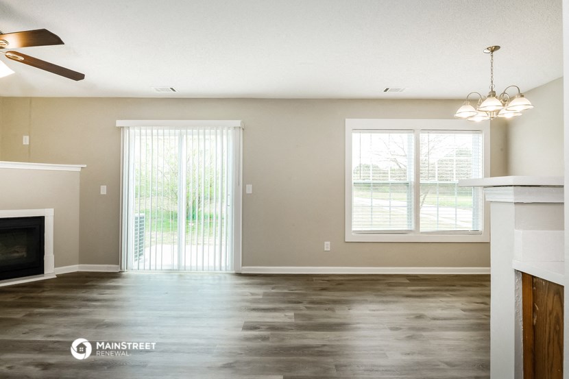 an empty living room with a fireplace and windows