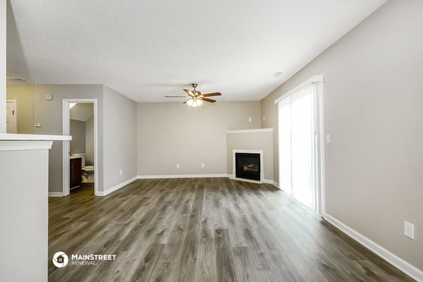 the spacious living room with fireplace and ceiling fan