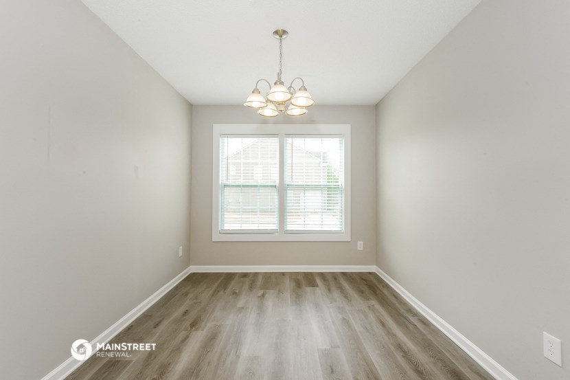 the living room of an apartment with wood flooring and a window