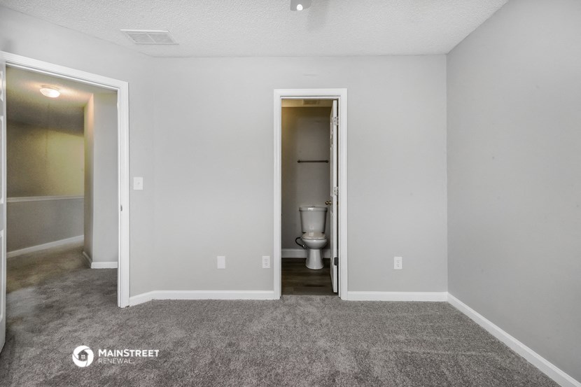 the living room of an apartment with a toilet and a hallway to the bathroom
