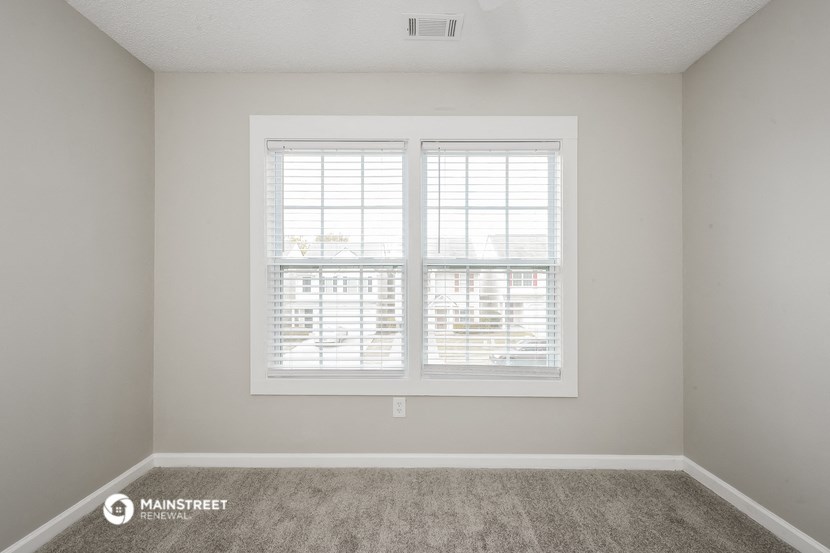 the living room of an empty apartment with two windows