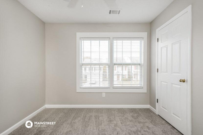 the spacious living room of a manufactured home with a white door and window