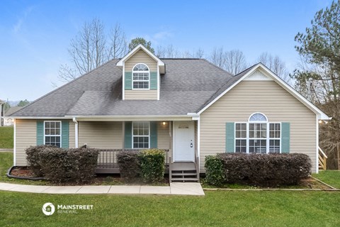 a tan house with green shutters and a front porch
