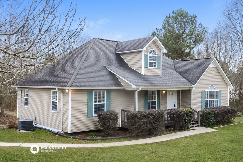 a beige house with blue windows and a yard