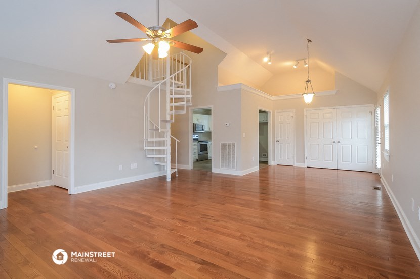 an empty living room with a staircase and a ceiling fan