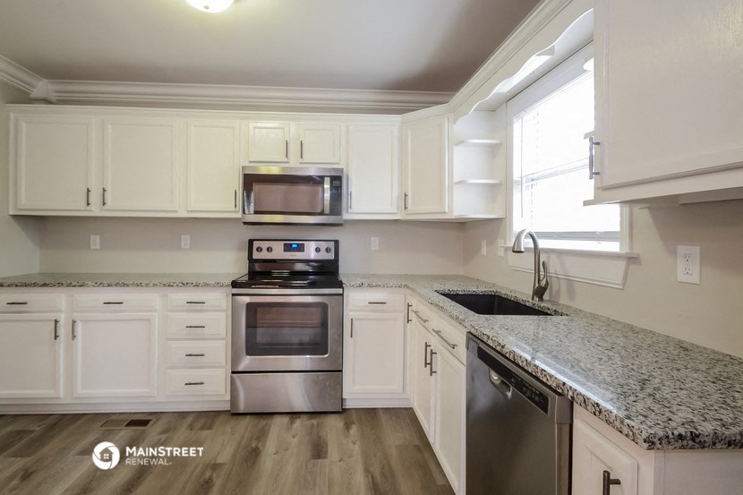 a white kitchen with granite counter tops and stainless steel appliances