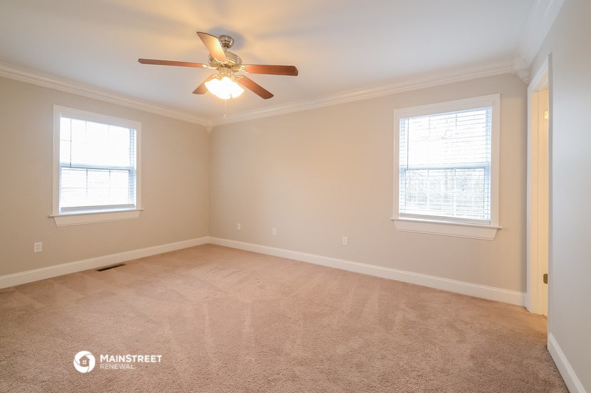 the bedroom with carpet and ceiling fan and two windows