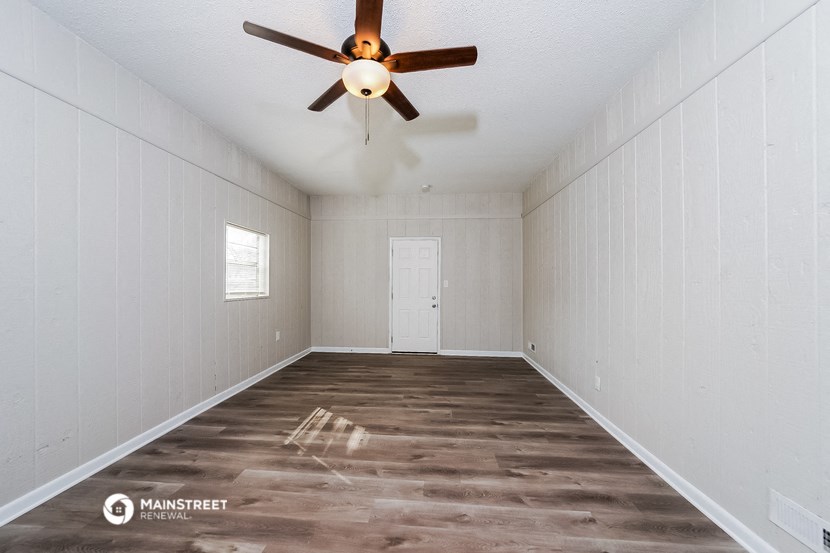 an empty room with a ceiling fan and a door