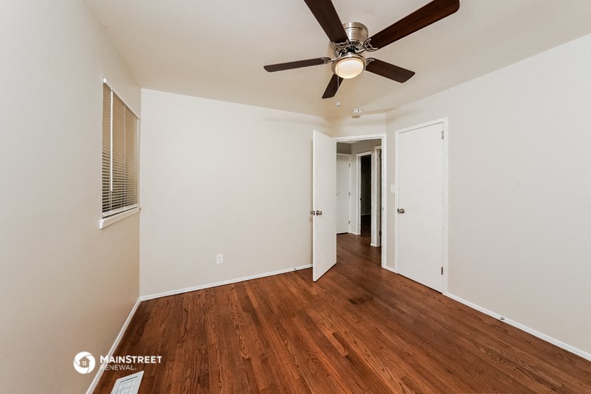 a bedroom with white walls and a ceiling fan