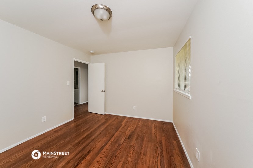 a spacious living room with hardwood flooring and white walls