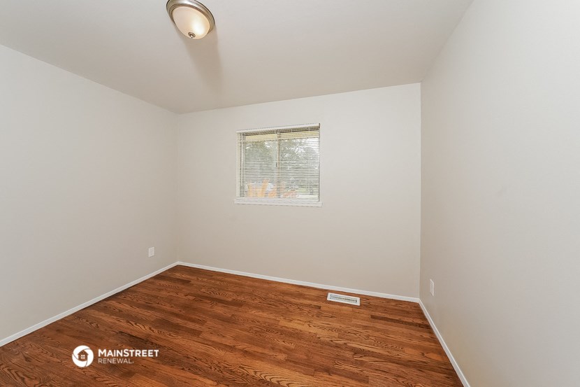 a spacious room with hardwood flooring and a window