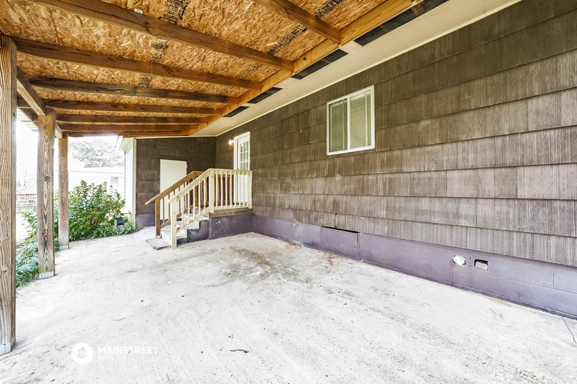 a covered porch with a wooden ceiling and a staircase