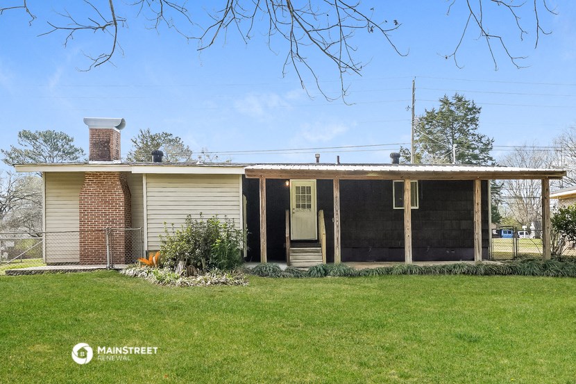 the front of a small house with a lawn and a fence