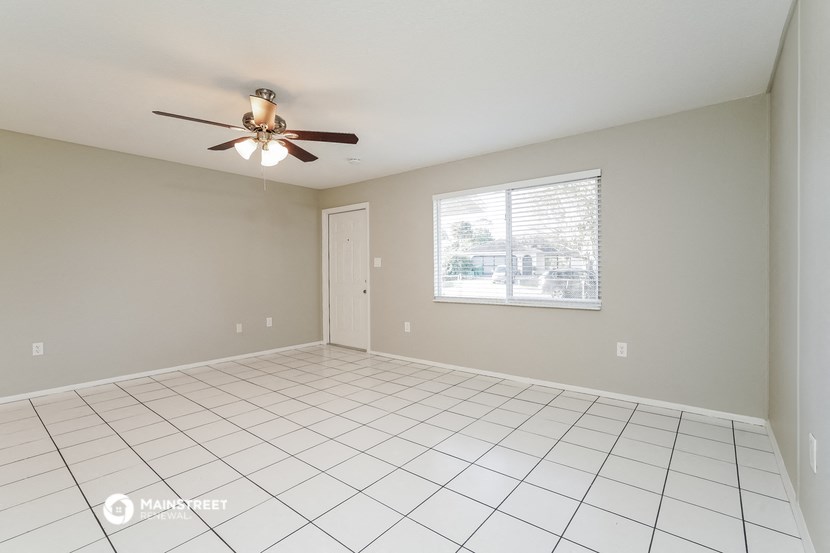 an empty living room with a ceiling fan and a window