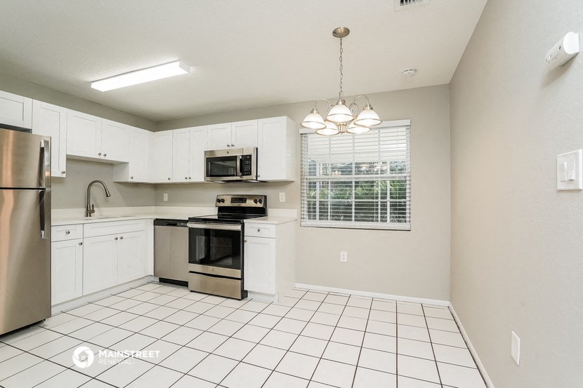an empty kitchen with white cabinets and stainless steel appliances