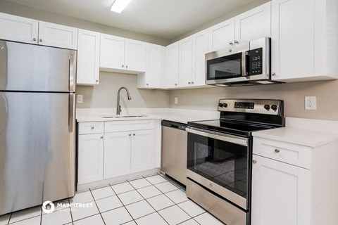 a white kitchen with stainless steel appliances and white cabinets