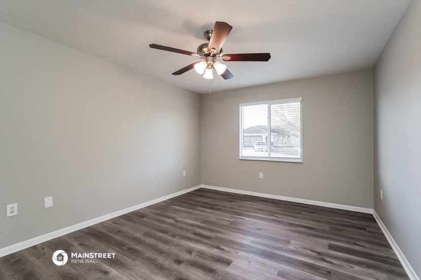 the spacious living room has a ceiling fan and a window