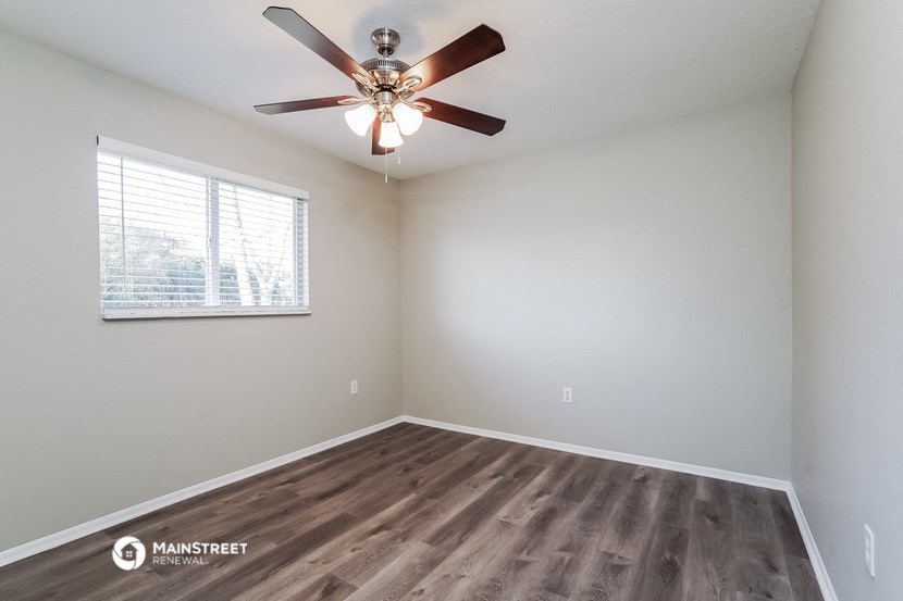 an empty room with a ceiling fan and a window