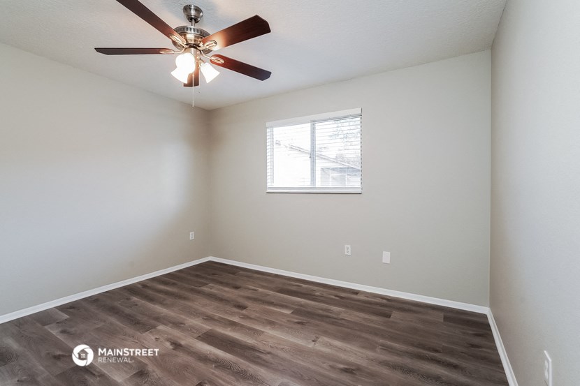 the bedroom has a large window and a ceiling fan