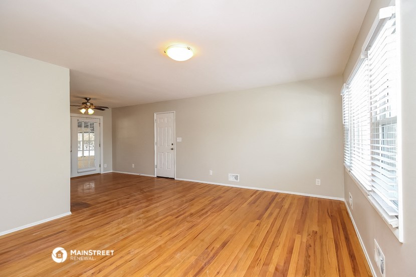 the spacious living room with wood flooring and large windows