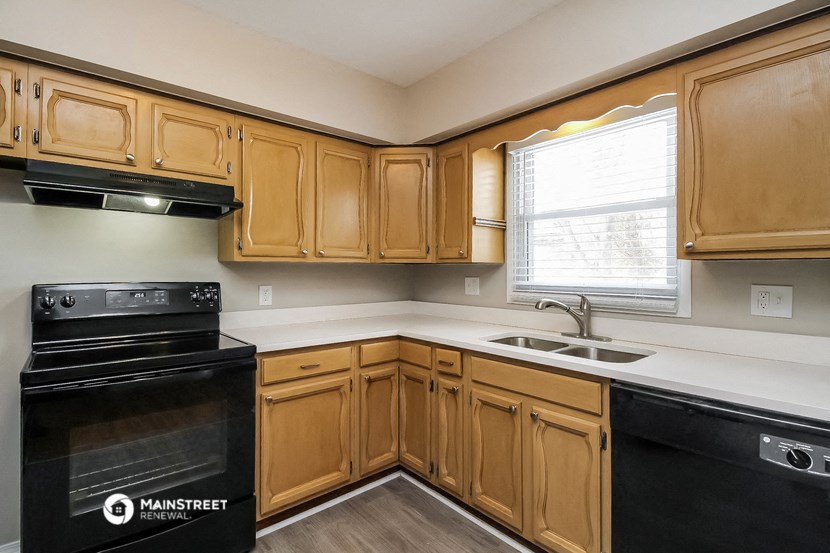 an empty kitchen with wooden cabinets and black appliances
