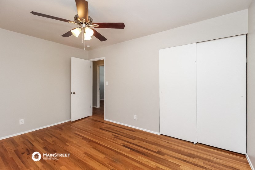 a bedroom with white walls and a ceiling fan