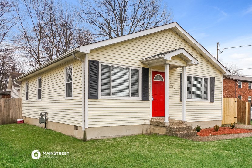 a yellow house with a red door on a lawn