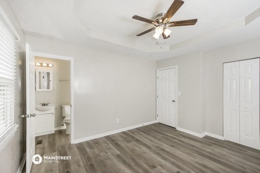 an empty bedroom with a ceiling fan and a bathroom