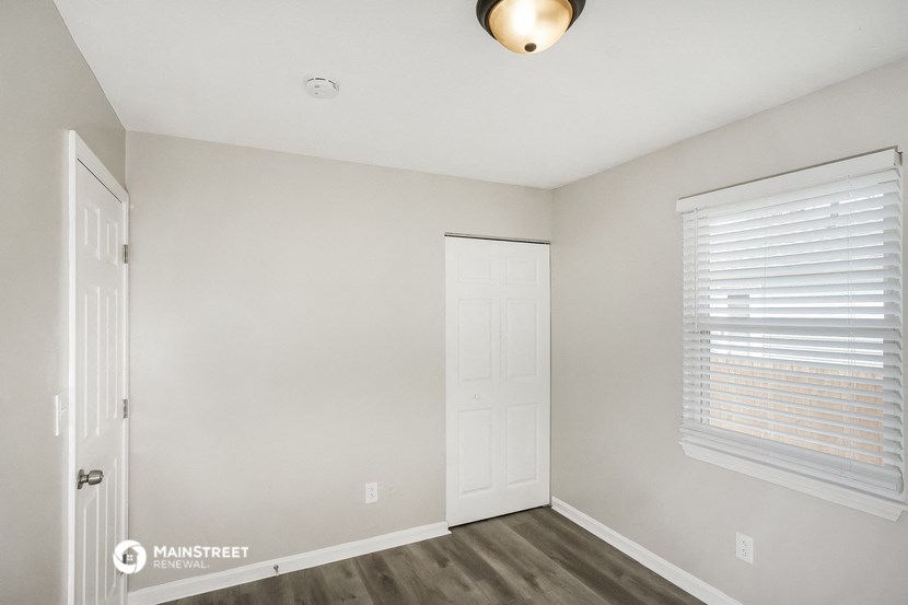 the living room of an apartment with a door and a window