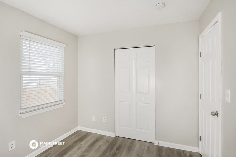 a bedroom with white walls and a white door and a window