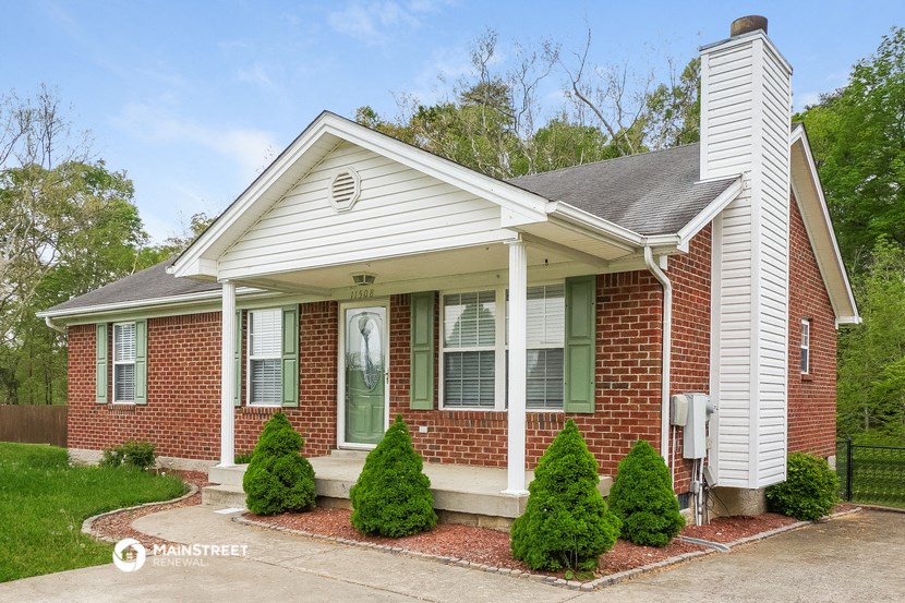 a small red brick house with white siding and a porch