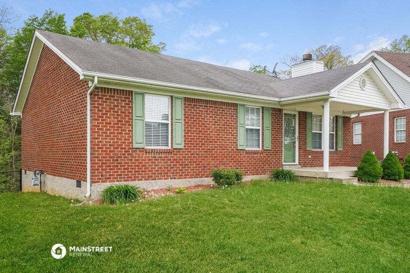 a brick house with green window shutters and a lawn