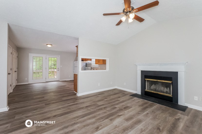 a living room with a fireplace and a ceiling fan