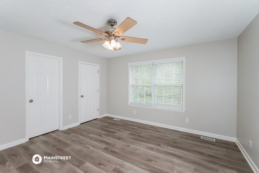 the spacious living room with a ceiling fan