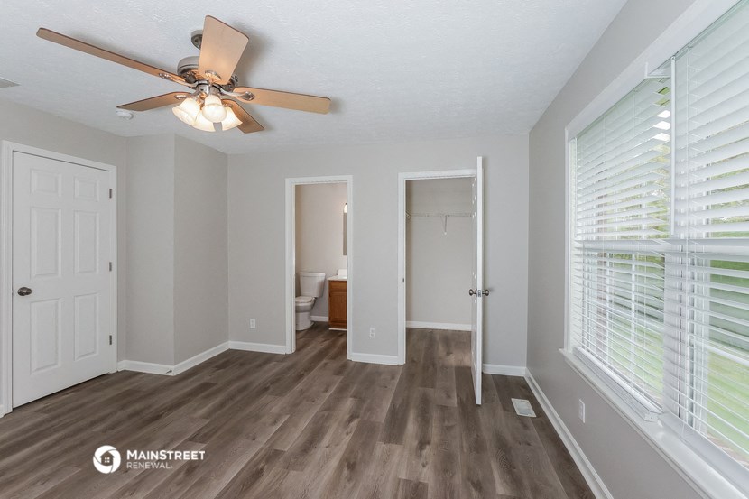 the spacious living room with wood flooring and a ceiling fan