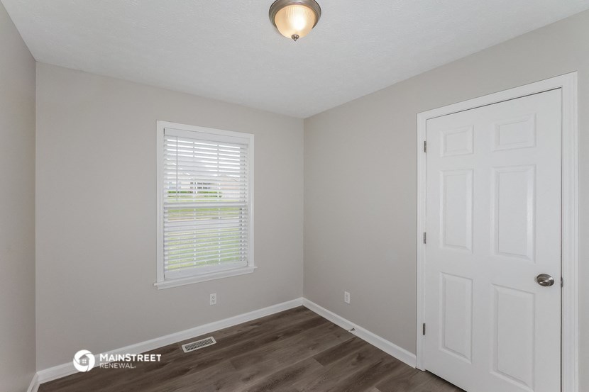 the interior of a bedroom with a white door and a window