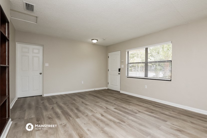 the spacious living room with a large window and wood flooring